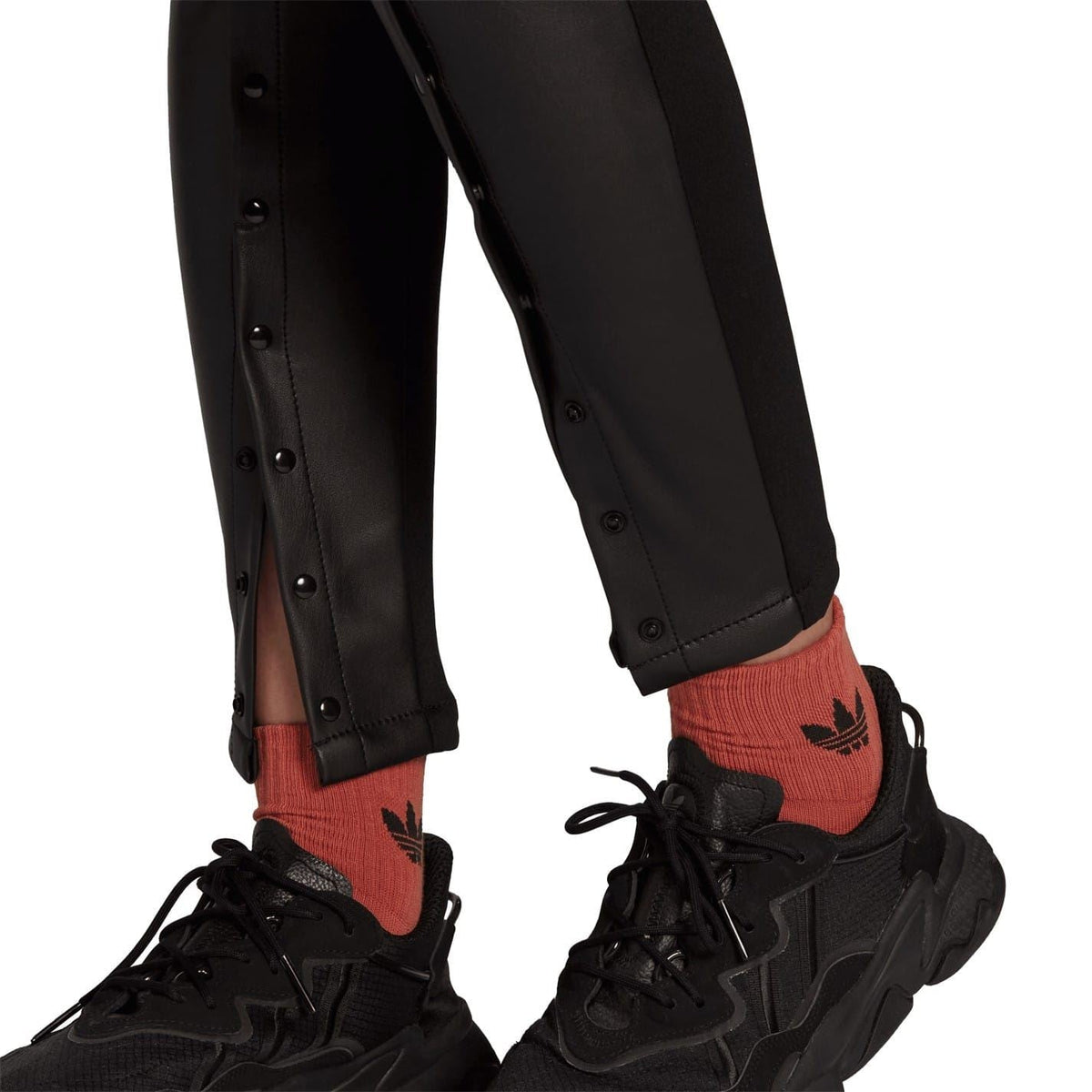 Black faux leather skinny trousers hem with button placket detail near cuffs