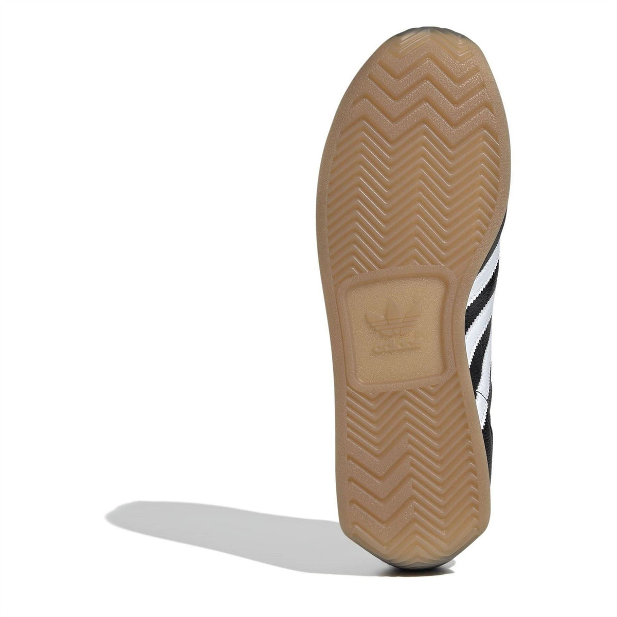 Gum rubber outsole with zigzag tread pattern on a black sneaker.
