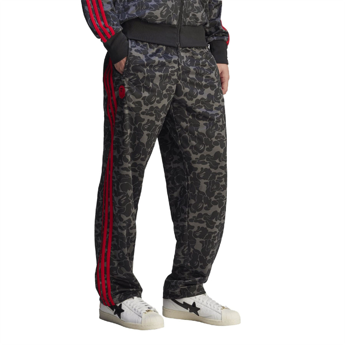 Close-up camo trackpants with triple red side stripes and tapered ankle cuffs.