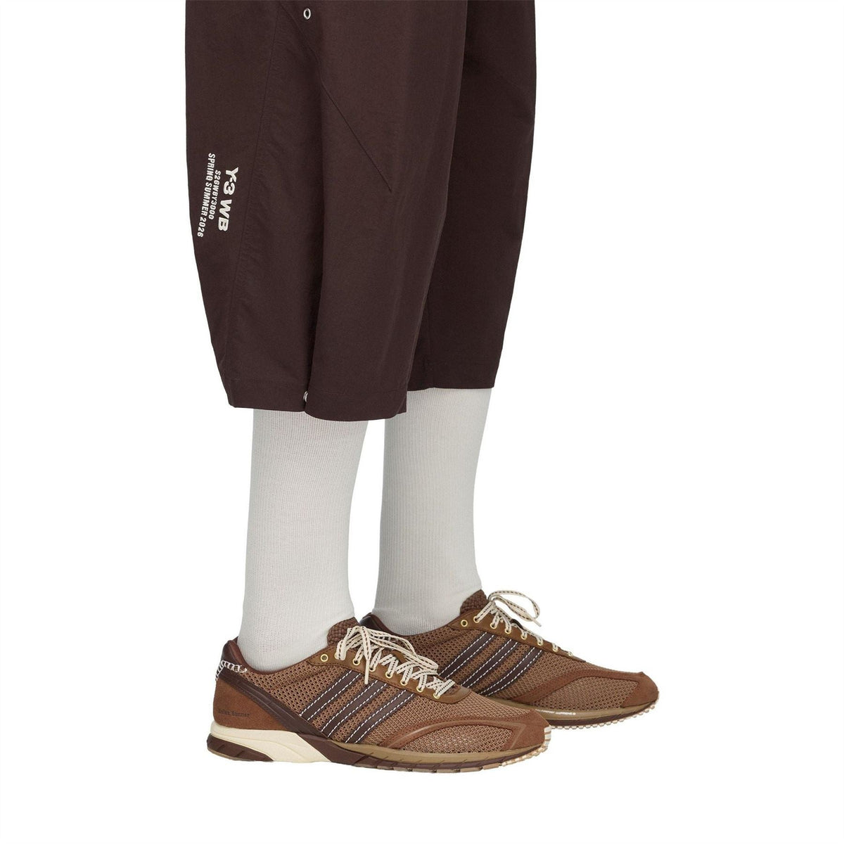 Close-up of brown shorts hem with Y-3 text logo and elastic waist drawstring