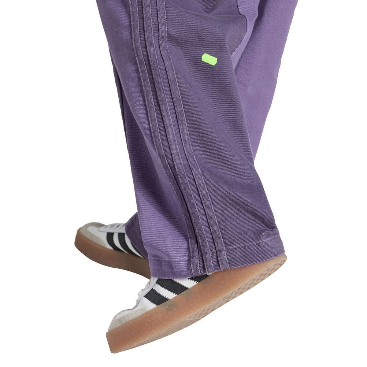Purple straight-leg jeans with contrast seam detailing and small neon green logo patch.