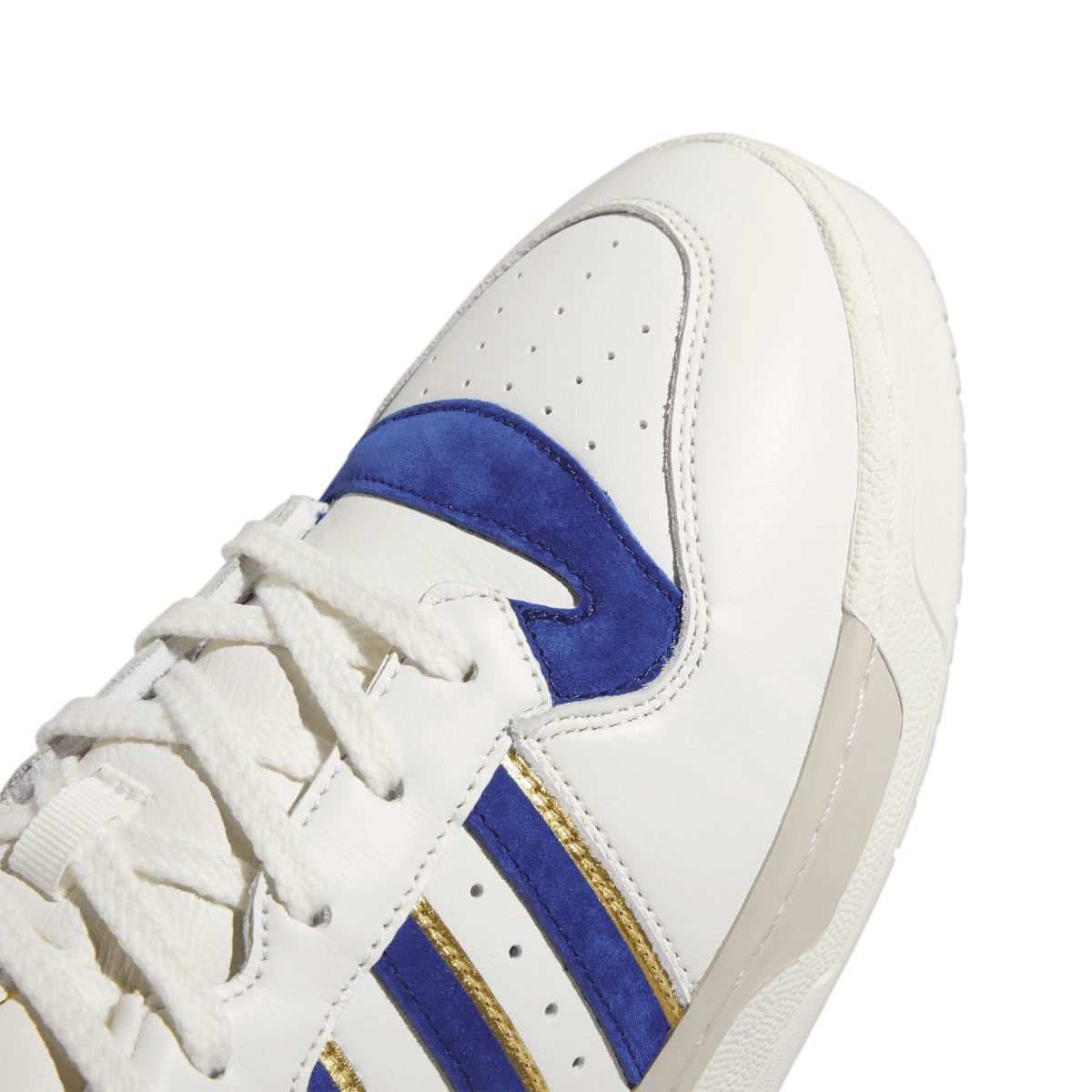 adidas Rivalry 86 low-top trainers close-up: white leather panel with blue-and-gold stripe
