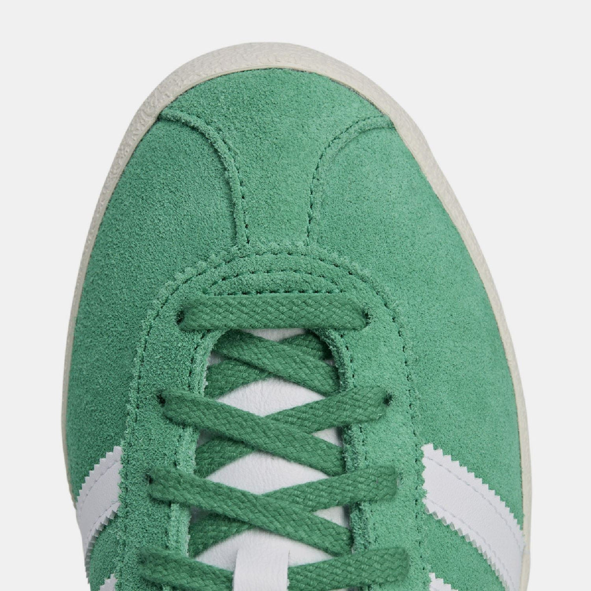 Close-up of green suede toe with green lace-up eyelets and perforation detail.