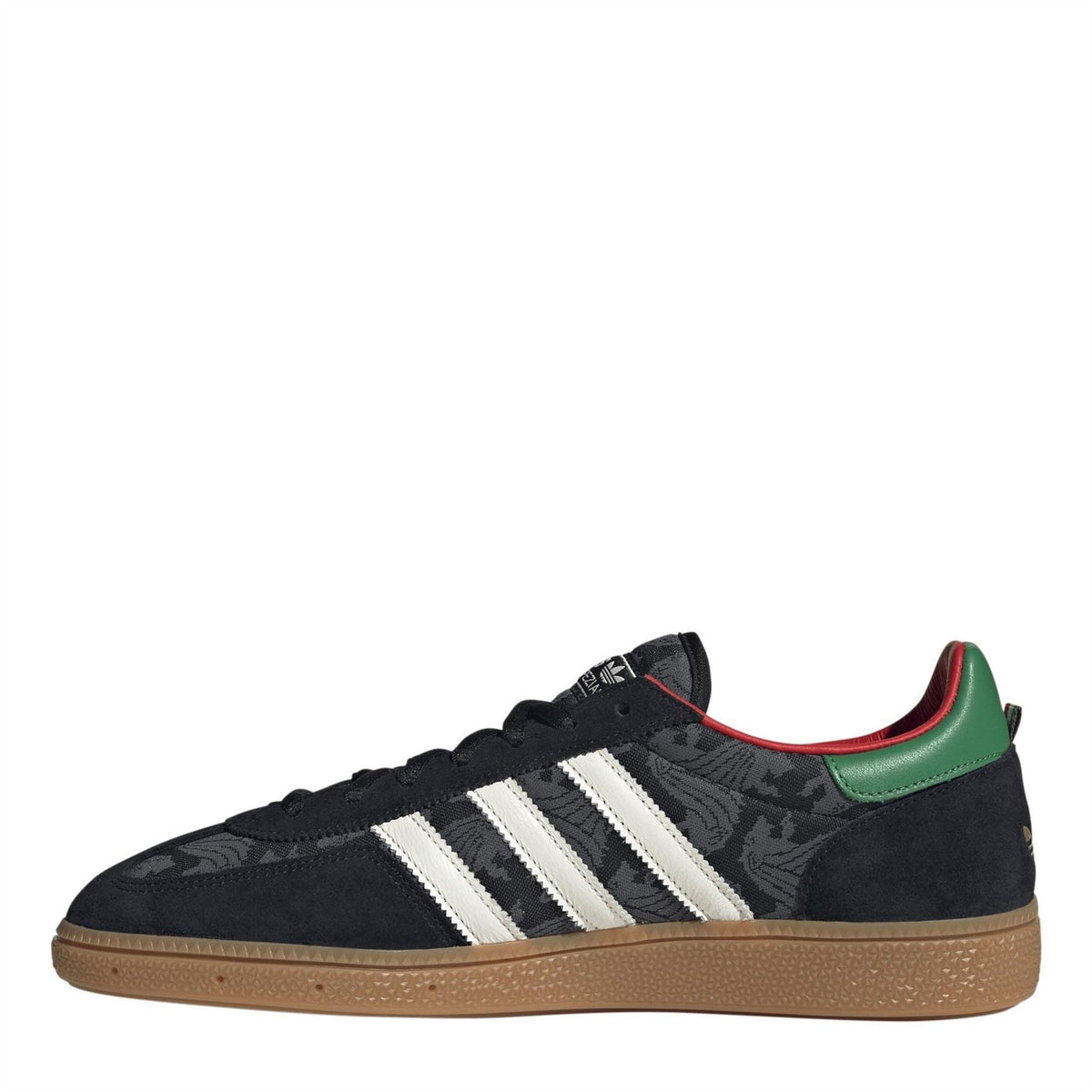 Black low-top adidas trainers with white three stripes and green heel collar accent