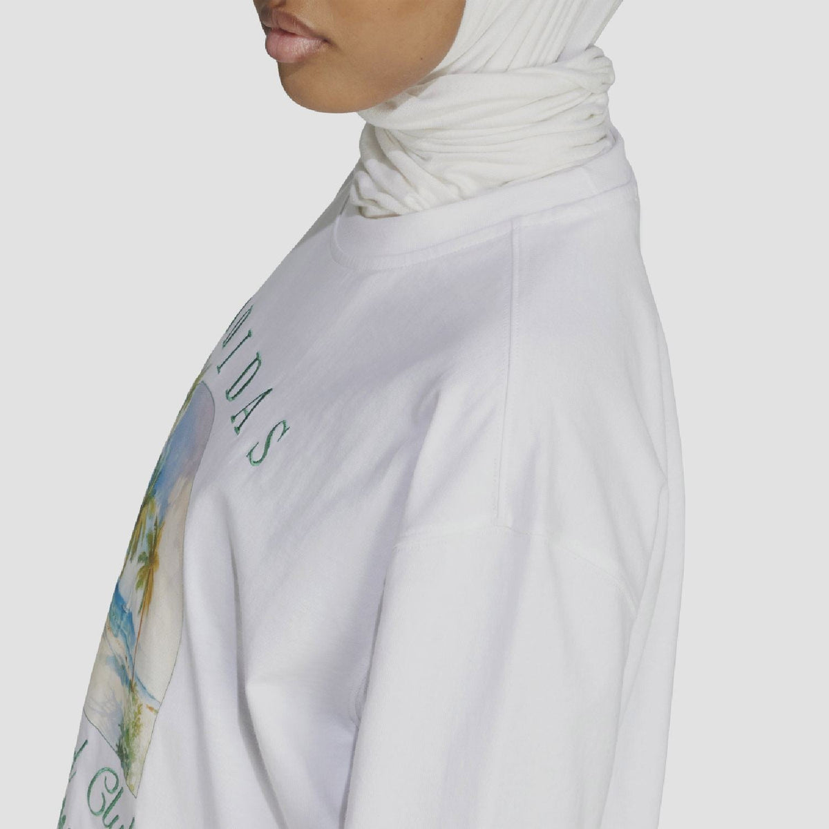 White oversized t-shirt side view with partial Adidas 'Island Club' graphic