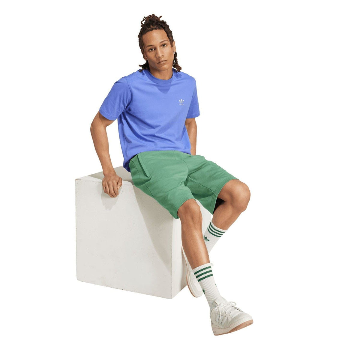 Green adidas Originals trefoil shorts on model, knee-length with elastic waist