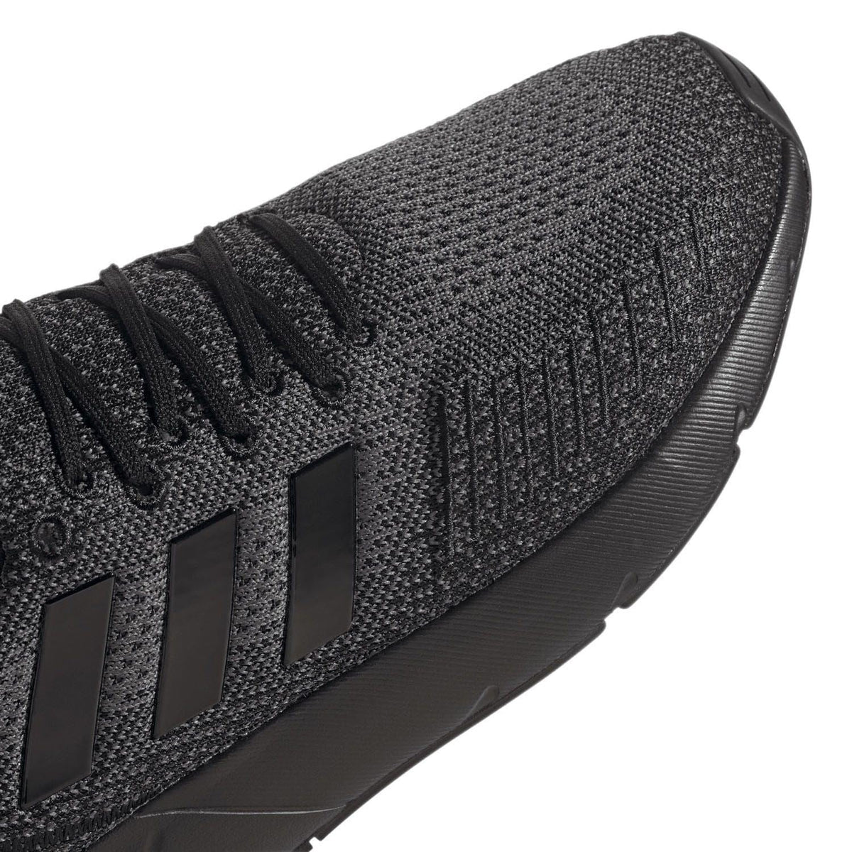 Black trainers close-up of knit side and embossed 3-stripe design