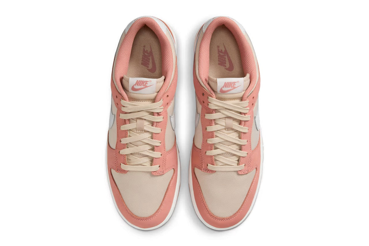 Pair of Nike Dunk Low sneakers, rear view, pink and cream uppers with NIKE heel text