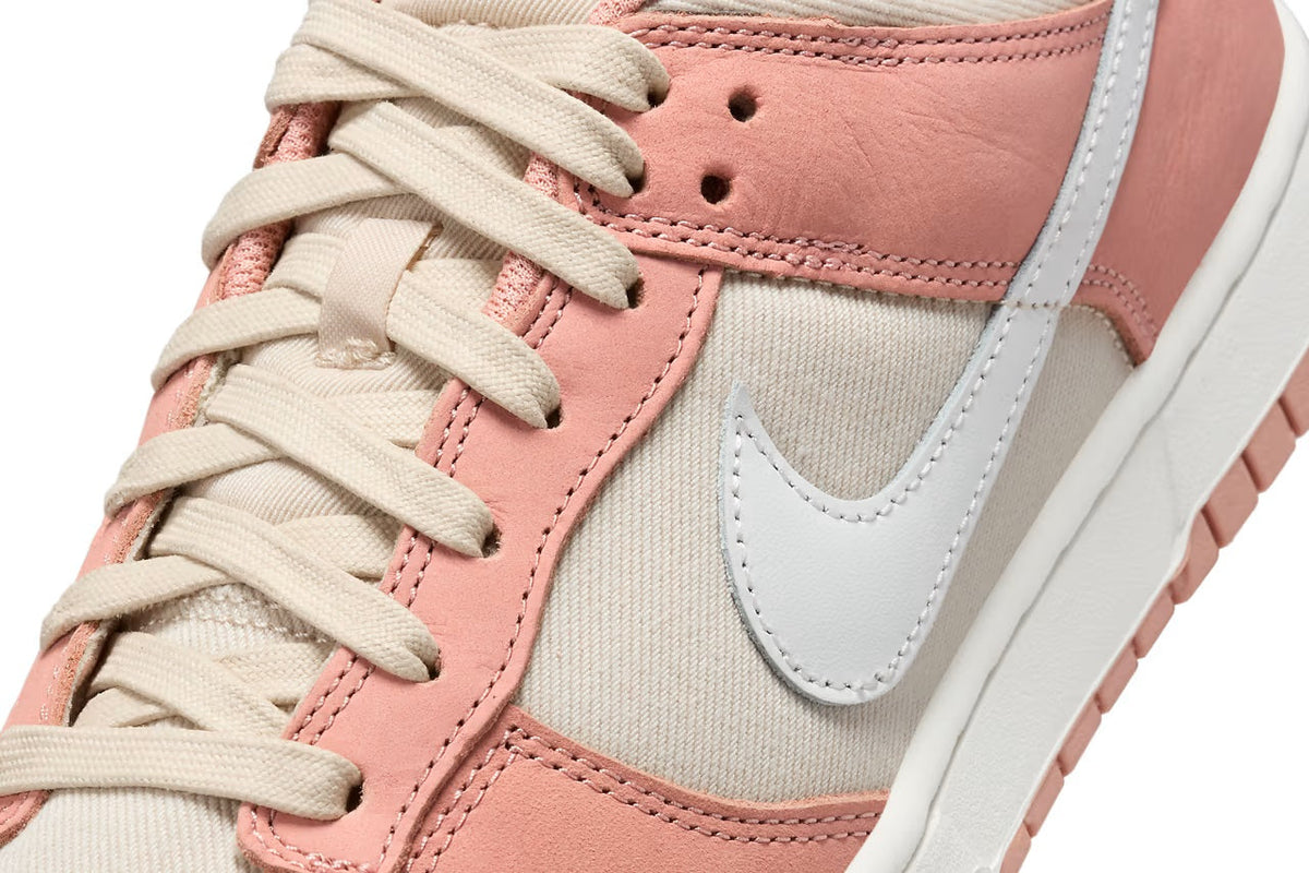 Close-up of Nike Dunk Low laces and swoosh, pink suede and cream textile panels