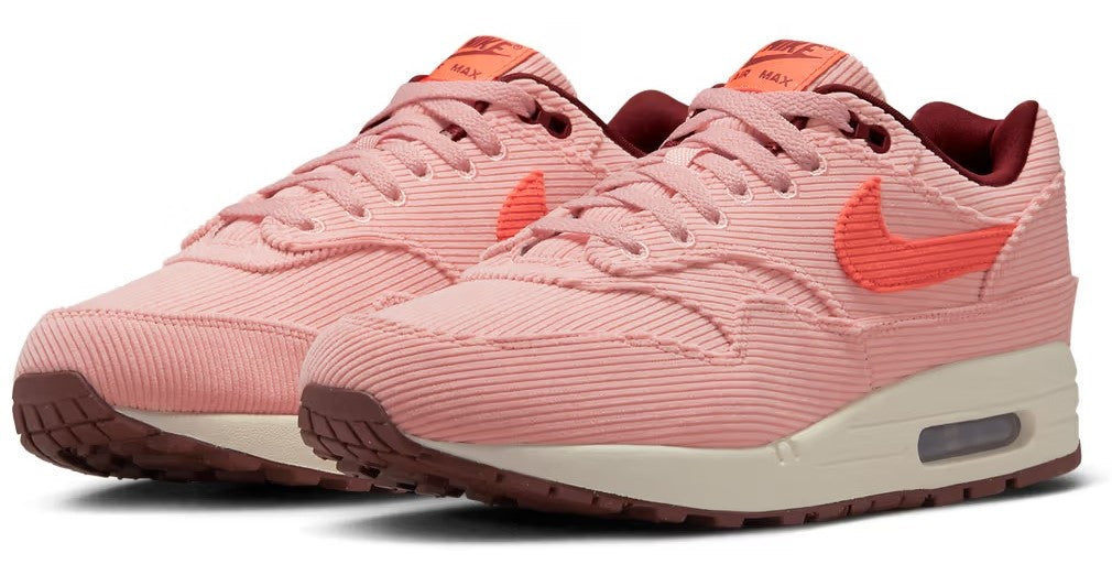 Nike Air Max 1 PRM coral-pink sneakers with orange Swoosh, lace-up front, and Air sole