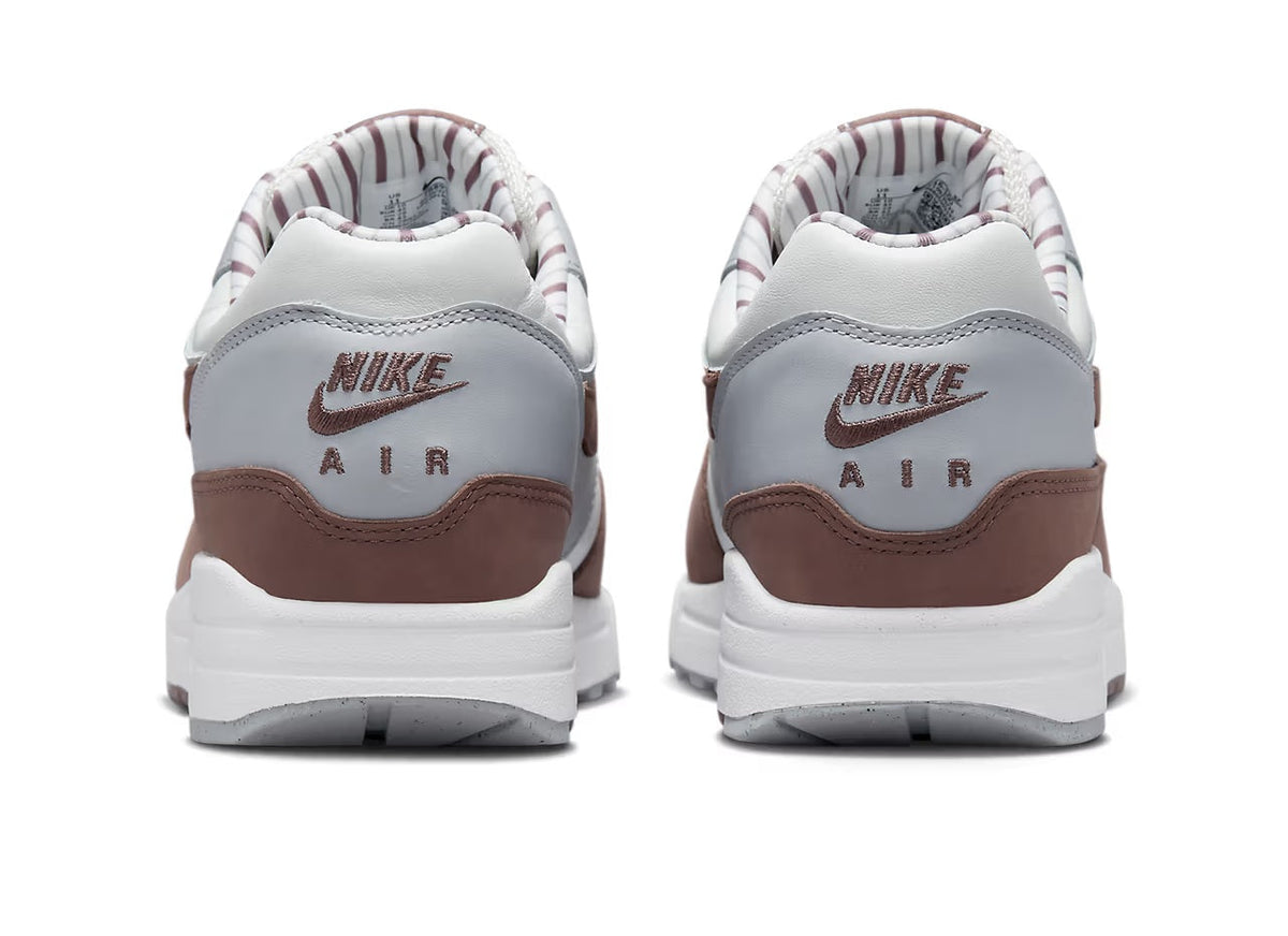 Back view of low-top sneakers: white leather with brown heel panel and Nike Air branding