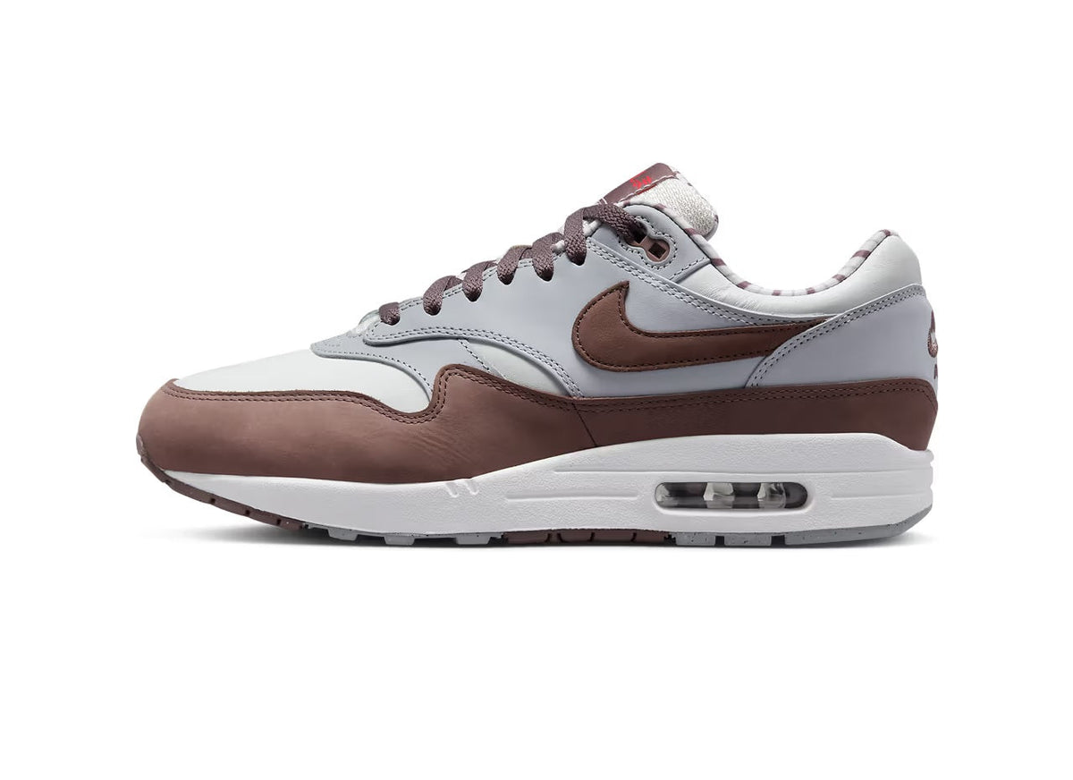 Low-top sneakers with white upper, brown overlays, and Air Max visible underfoot