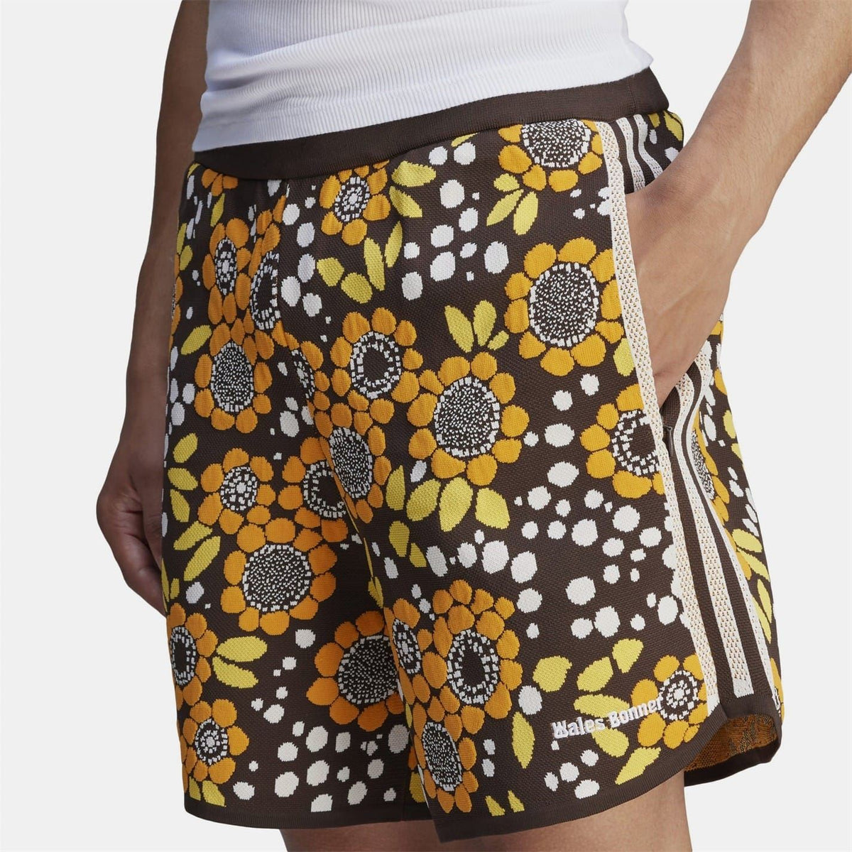 Close-up floral knit shorts with black base, large yellow flowers, and side stripe tape