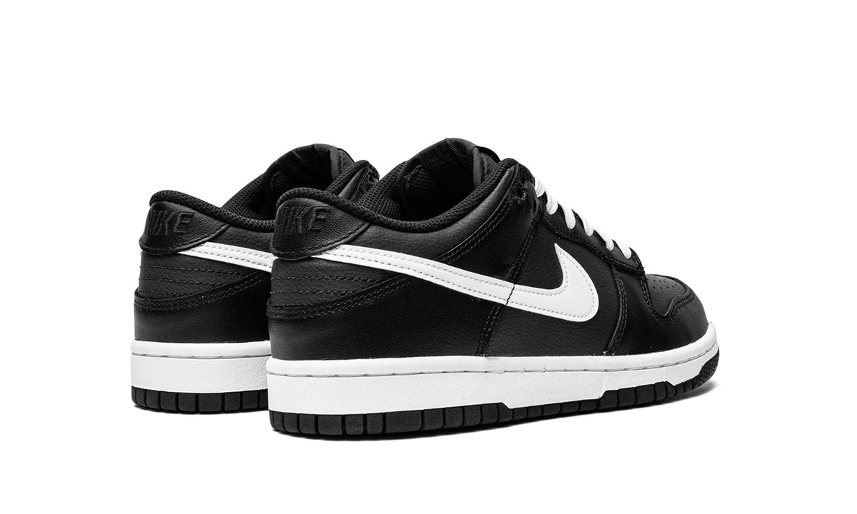 Kids' black low-top sneakers with white swoosh and padded collar