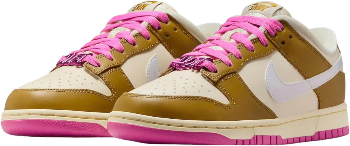 Pair of low-top sneakers in gold with white swooshes and bright pink laces