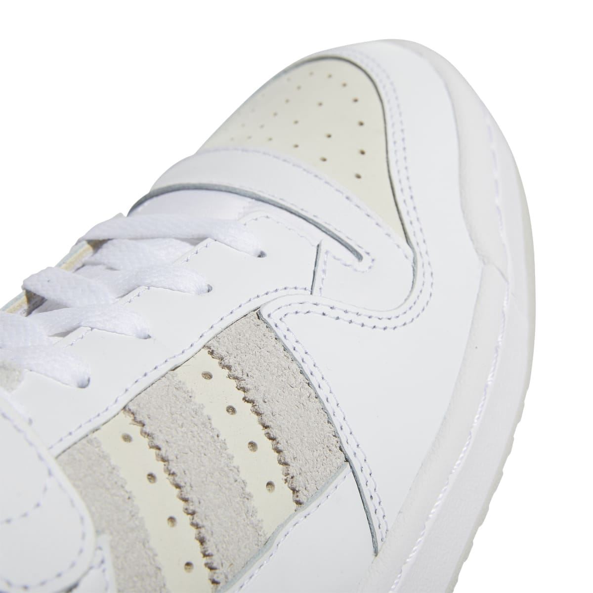 Close-up of white trainer upper with grey suede stripe panel and stitched overlays