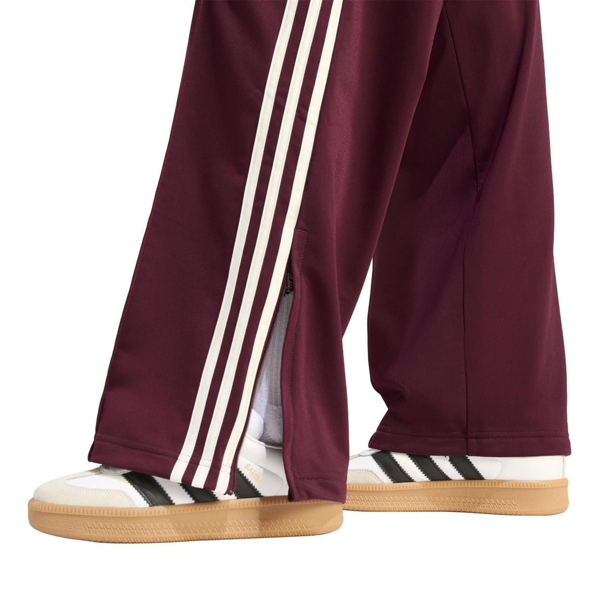 Maroon track pants with white side stripes, vented hem, and elastic ankle cuff