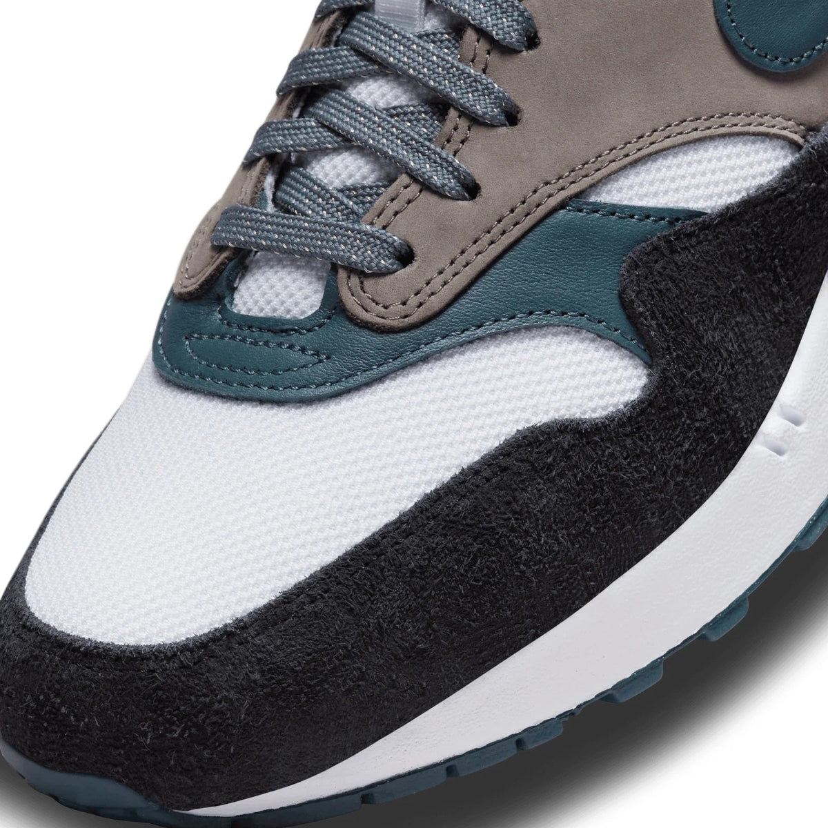 Close-up of sneaker upper with laced gray eyelets, suede overlays, teal trim, textured panel