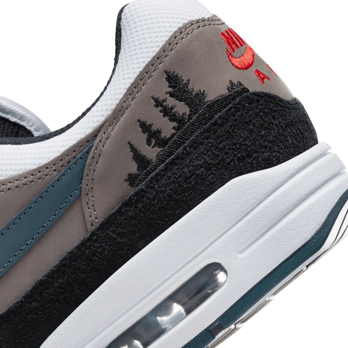 Close-up of heel and side with embroidered tree motif, red swoosh, black suede panel