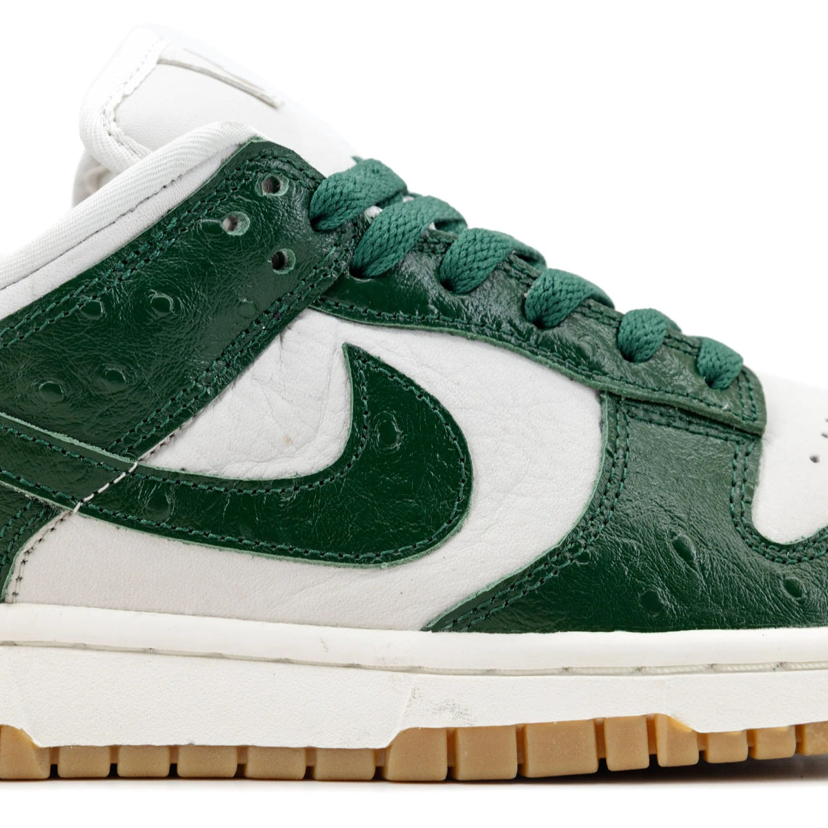 Women's low-top sneaker quarter close-up, dark green leather with white swoosh detail.