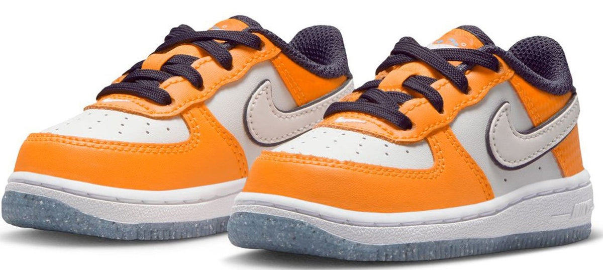 Pair of orange and white low-top Nike sneakers with navy laces and Swoosh