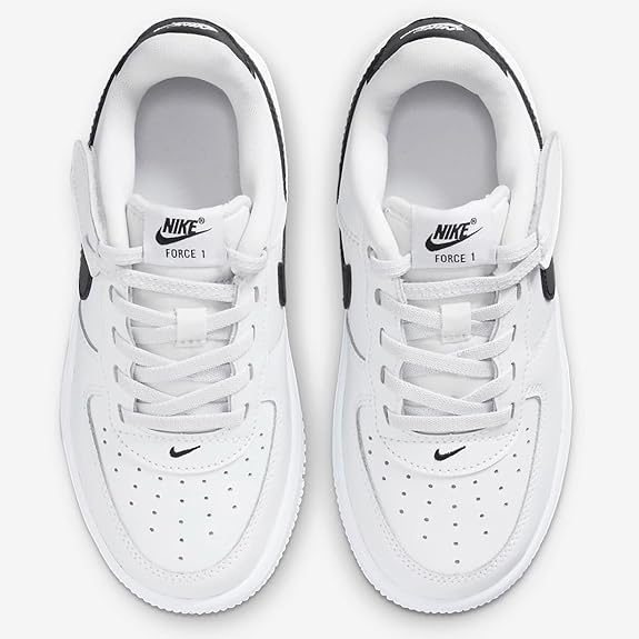Pair of white kids sneakers with white laces, perforated toe, and black Swoosh