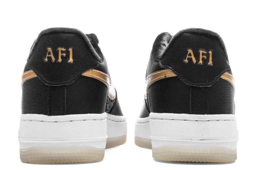 Kids AF1 logo heel tabs on black low-top sneakers with gold trim and white sole