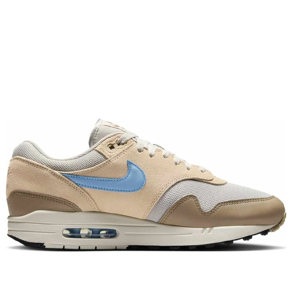 Men's Nike Air Max 1 ESS sneakers, angled view; light bone uppers and blue swoosh