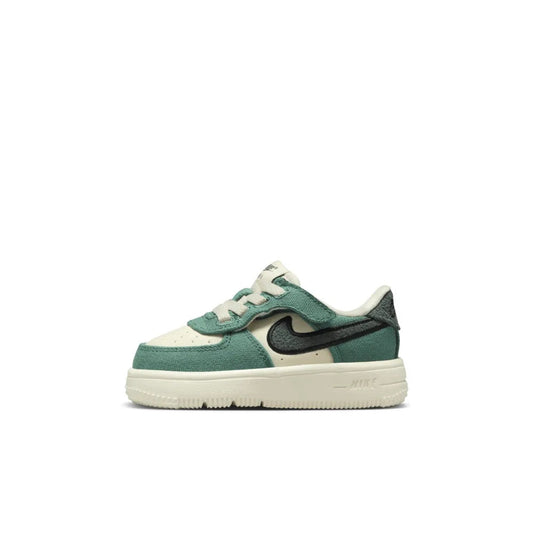 Toddler low-top sneaker with cream upper, green overlays, and black Swoosh