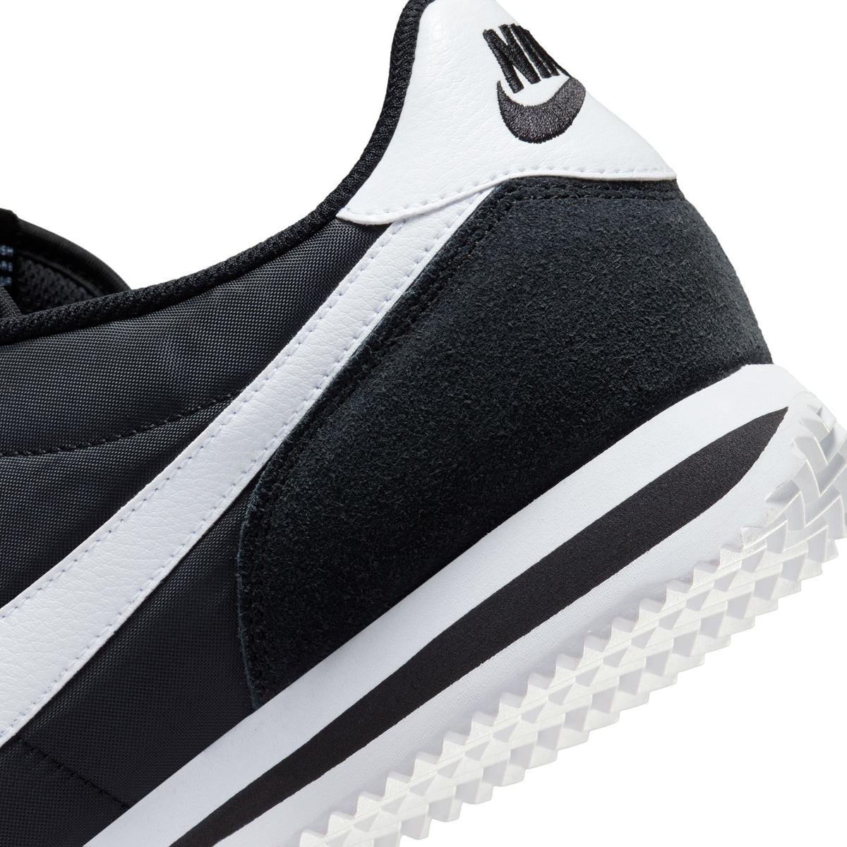 Nike Cortez TXT sneaker close-up, black suede and mesh with white stripe, grippy sole