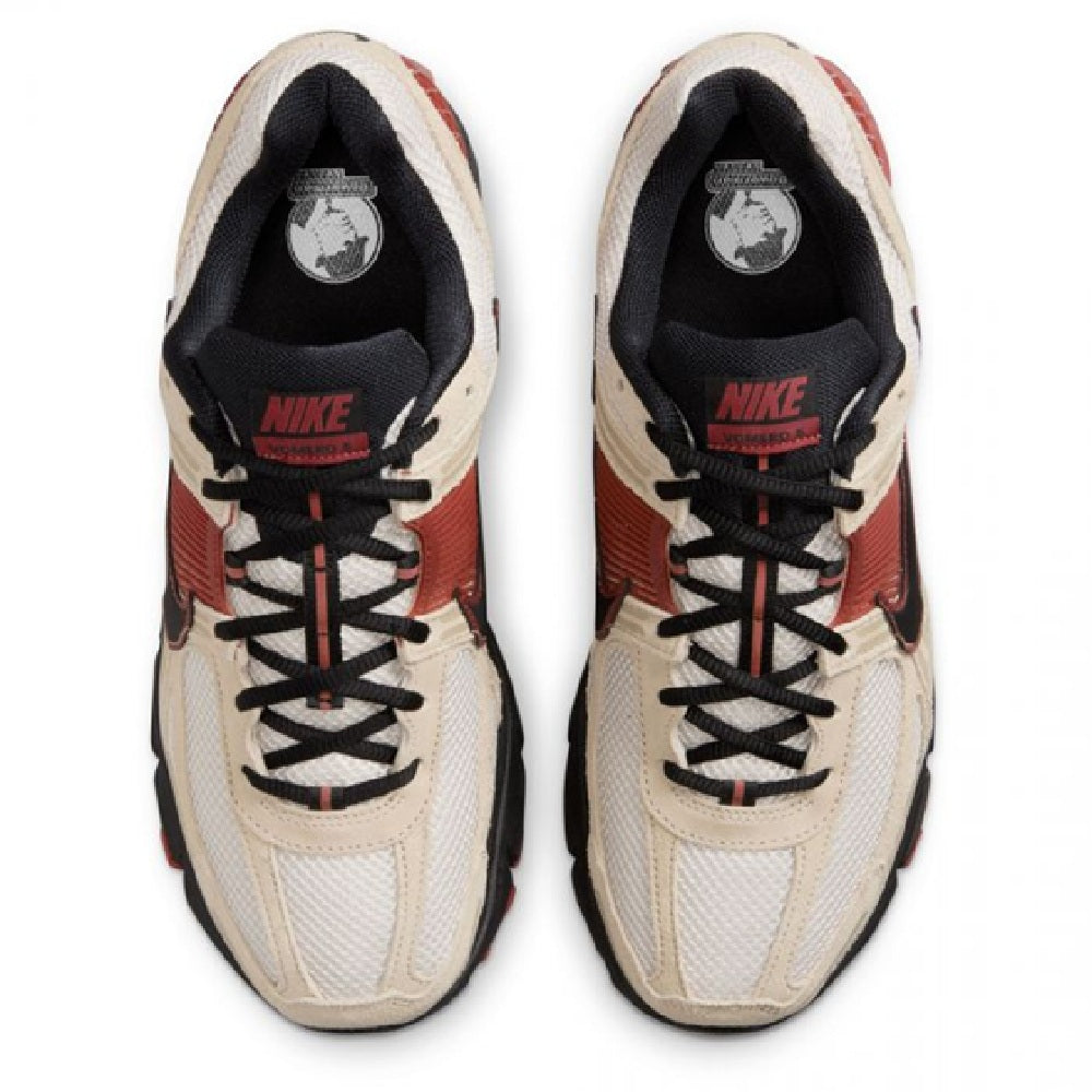 Nike Zoom Vomero 5 pair with black tongue lining, tan uppers, and red accents near laces