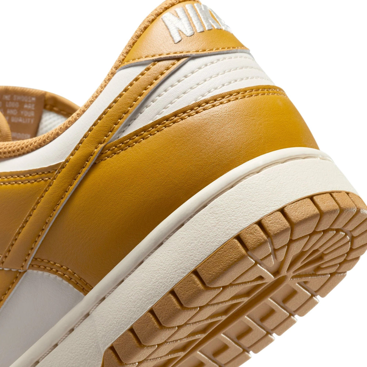 Nike Dunk Low retro sneakers close-up: wheat leather with stitched swoosh and textured sole