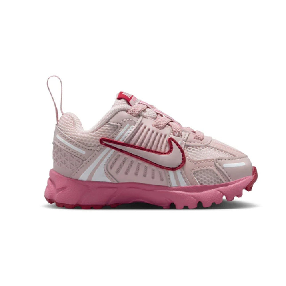Toddler Nike lace-up running shoe in light pink with red swoosh and cushioned midsole.