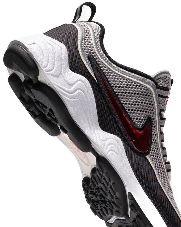 Close-up of running sneaker side and outsole: metallic silver upper, red Swoosh, black sole