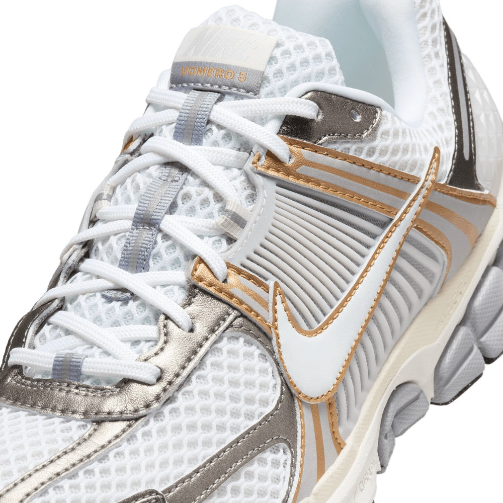 Close-up of white mesh upper with gold trim, gray eyestay, and white laces