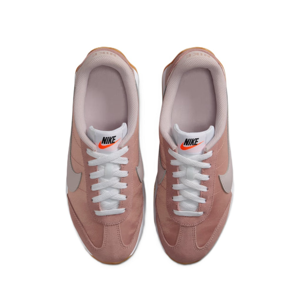 Women’s Nike sneakers with white laces, dusty pink upper, and light gray lining