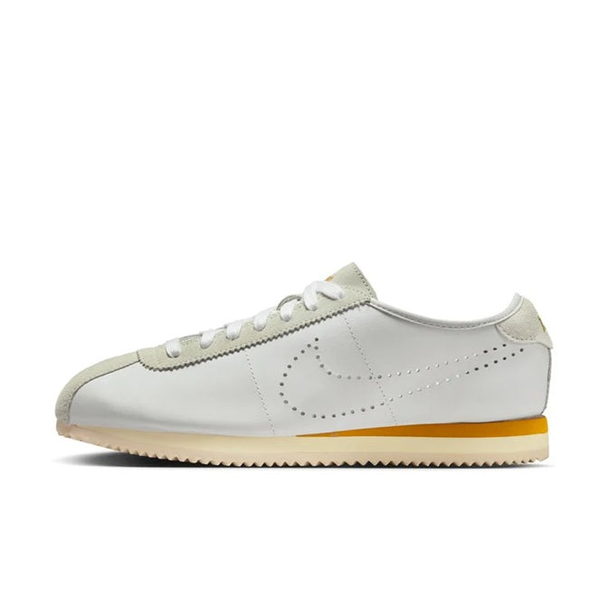 Low-top sneakers in light bone/white with suede collar, bronze swoosh, and gum outsole