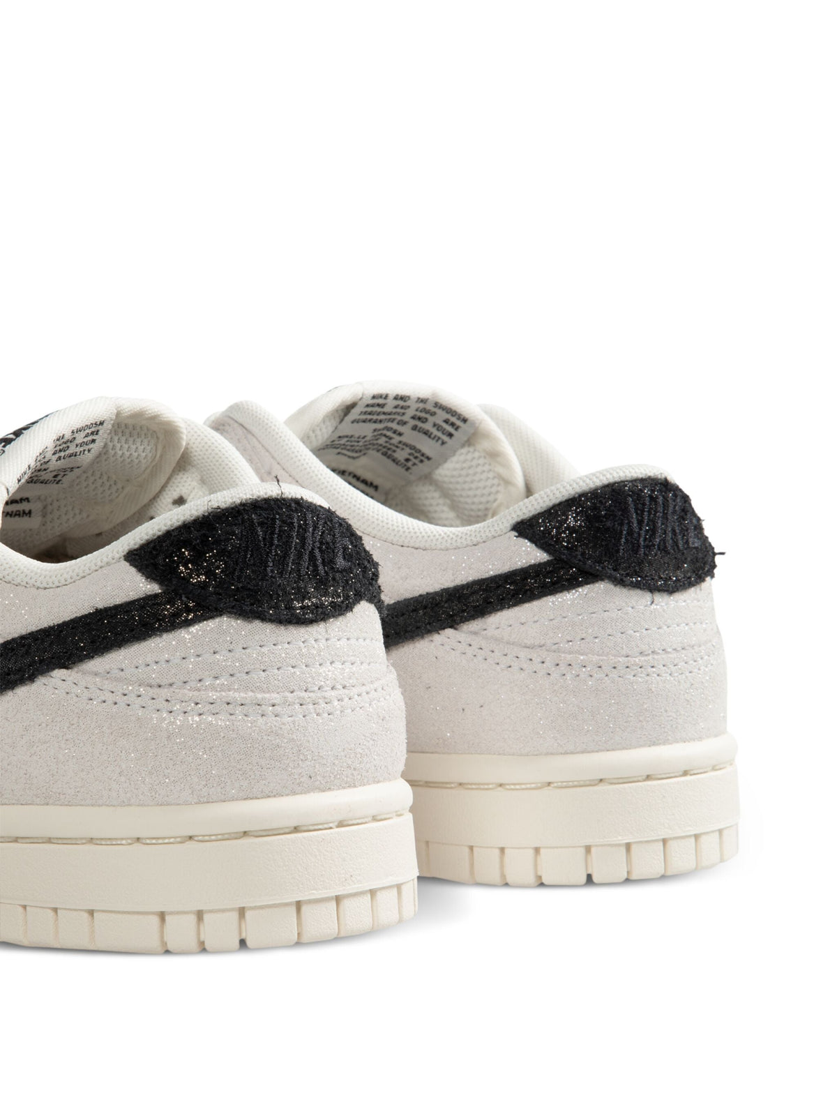 Nike Dunk Low SE heel view, white upper with black textured Swoosh and gum sole.