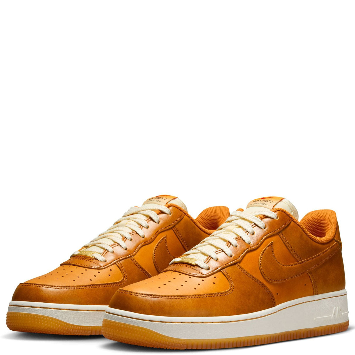 Pair of tan-orange suede Nike sneakers with white laces and cushioned platform sole