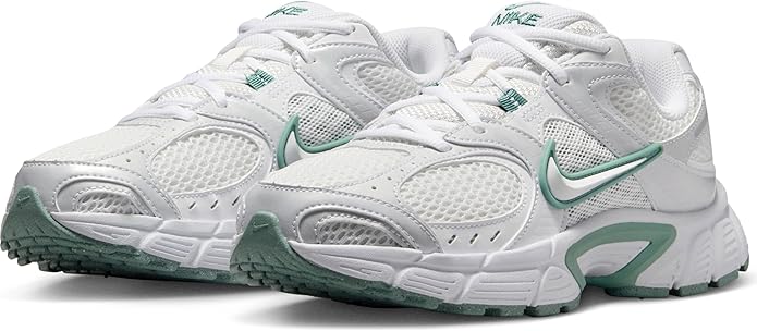 White athletic sneakers with green accents, padded collar, and layered cushioning