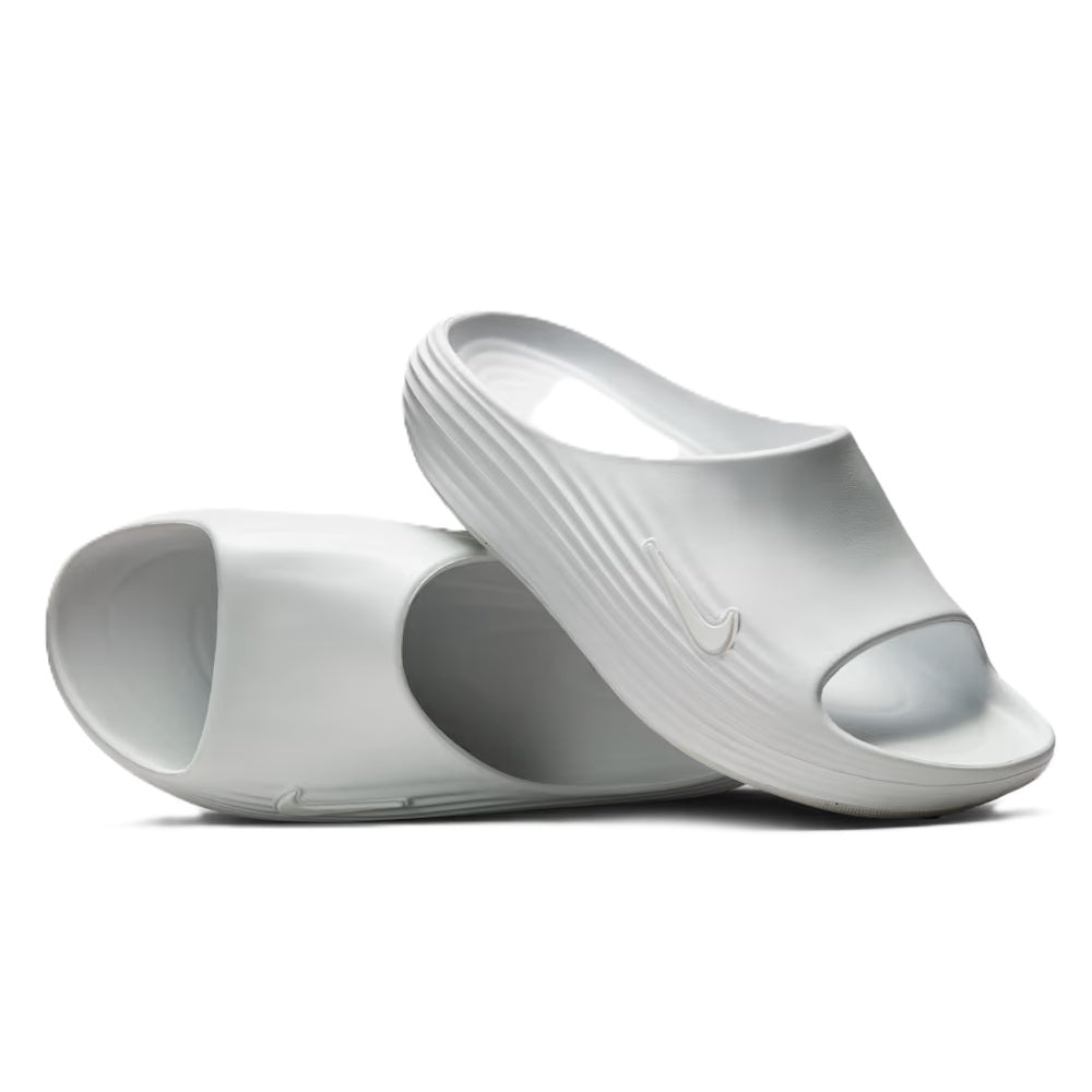 White slide sandals showing open toe, molded footbeds, and swoosh branding