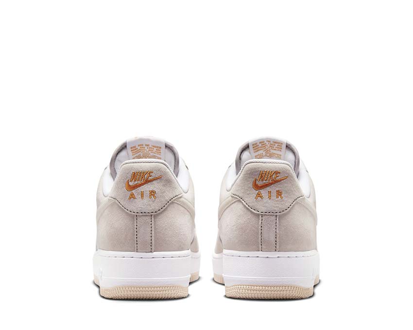 Beige low-top sneakers showing Nike Air heel text and white rubber sole