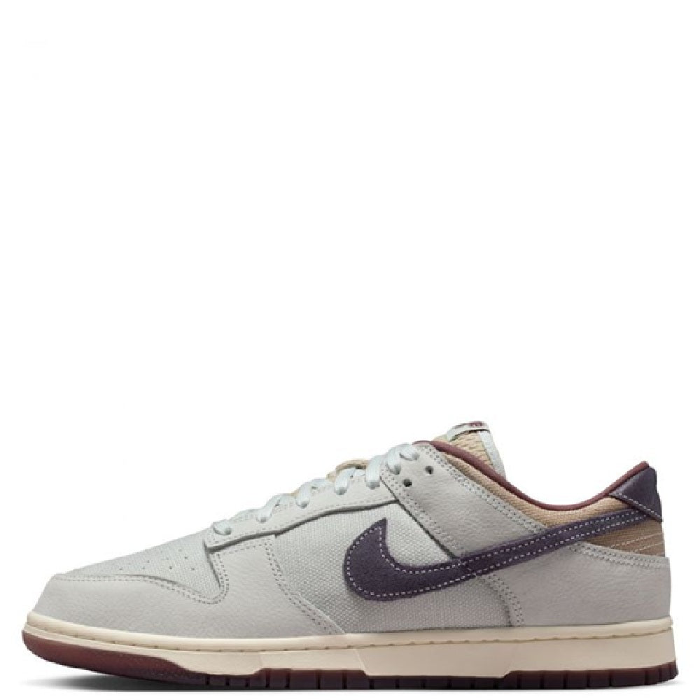 Nike Dunk Low Retro SE sneakers in off-white with dark purple swoosh, low profile.