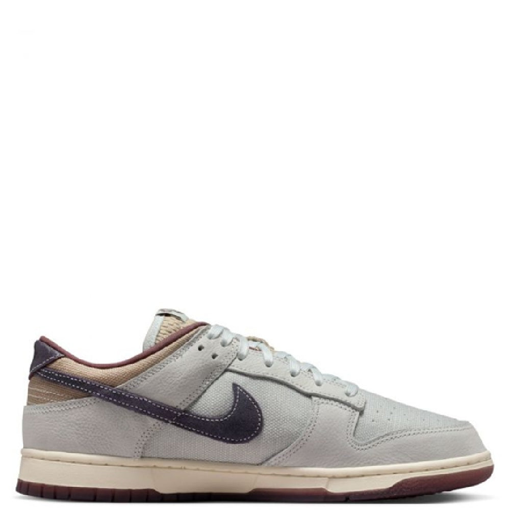 Nike Dunk Low Retro SE low-top sneakers, off-white uppers with purple side panel and laces.