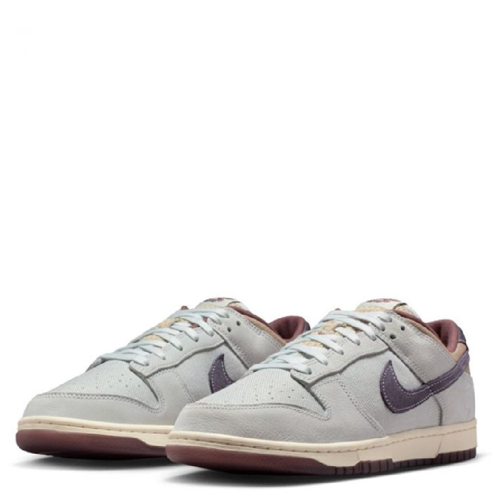 Nike Dunk Low Retro SE low-top sneakers, off-white leather with purple Swoosh accents.