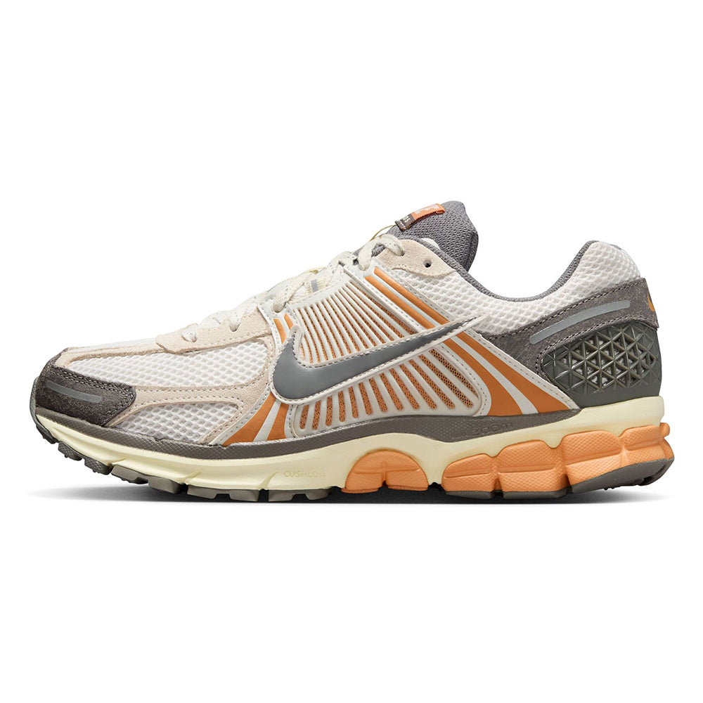 Nike Zoom Vomero 5 side view with cream mesh, orange stripe graphics, and dark gray heel