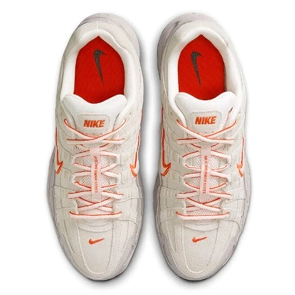 Pair of white sneakers with red insoles and orange swoosh on tongue