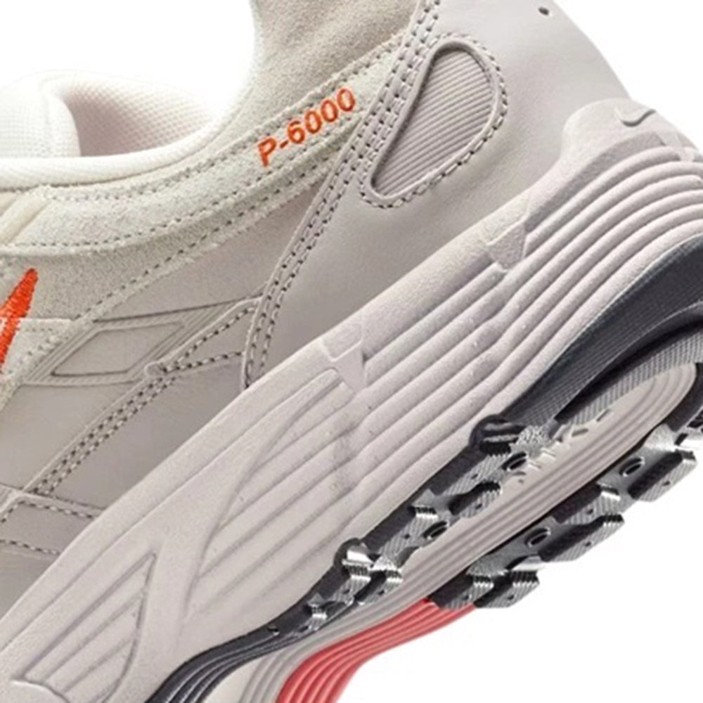 White P-6000 sneaker close-up with orange trim, textured midsole, and lace panel