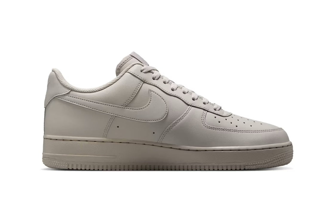 Nike Air Force 1 low-top sneakers in light grey, lace-up, side profile view.