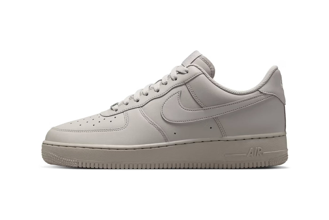 Nike Air Force 1 low-top sneakers in light grey leather, lace-up, front side view.
